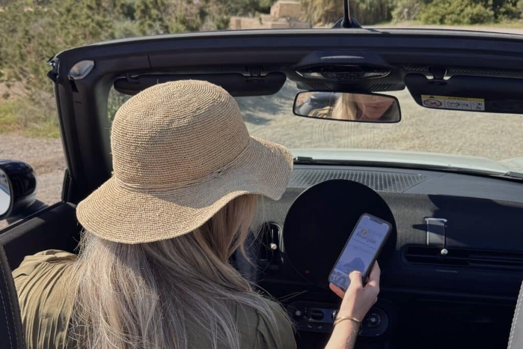Woman using digital Ibiza route plan on her phone during a road trip