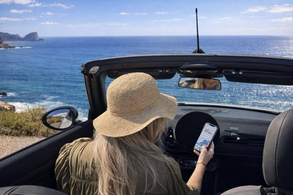 Traveler using Ibiza Routeplan on phone during a coastal self-drive in Ibiza