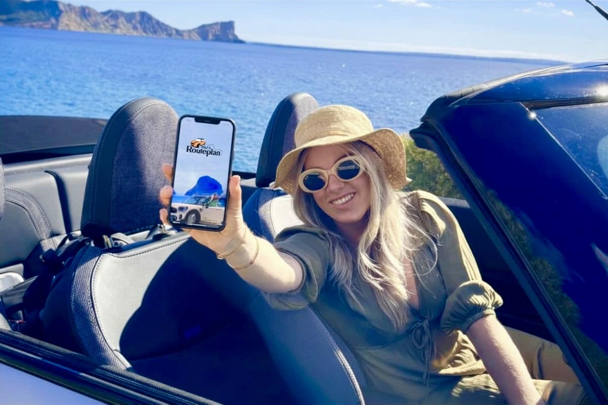 woman showing ibiza routeplan guide on her phone with the ibiza coastline behind